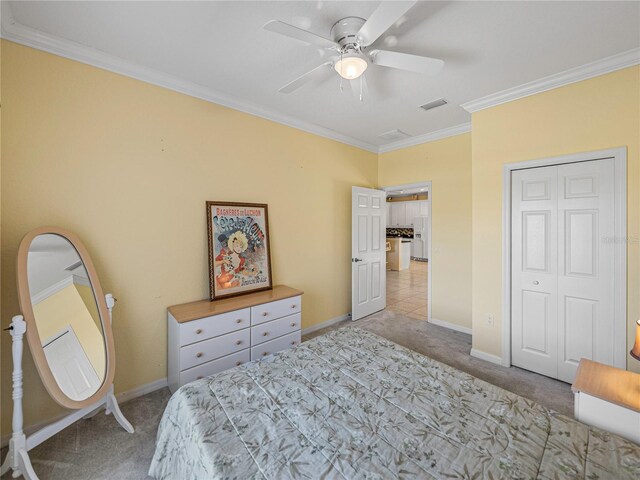 bedroom with ceiling fan, a closet, light colored carpet, and ornamental molding