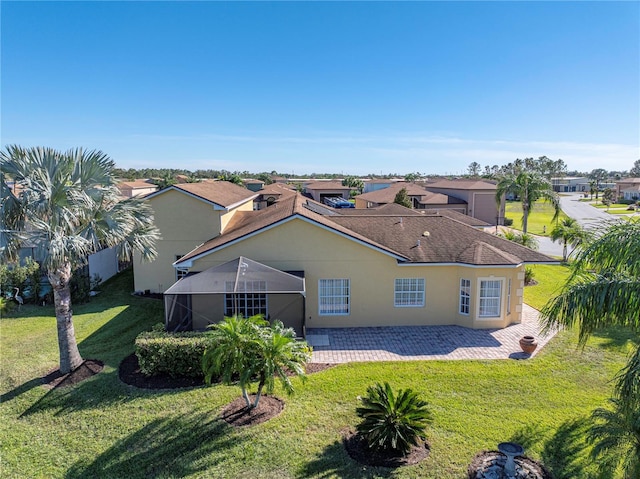 rear view of property with a patio, a lanai, and a lawn