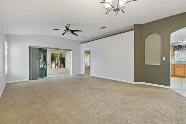 unfurnished room with ceiling fan with notable chandelier, light colored carpet, and vaulted ceiling