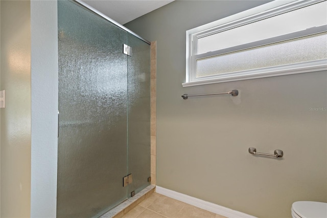 bathroom featuring tile patterned flooring, toilet, and a shower with door