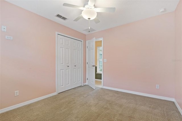 unfurnished bedroom featuring ceiling fan, light colored carpet, and a closet