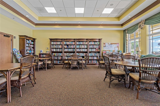 dining space with carpet, a paneled ceiling, ornamental molding, a raised ceiling, and a high ceiling