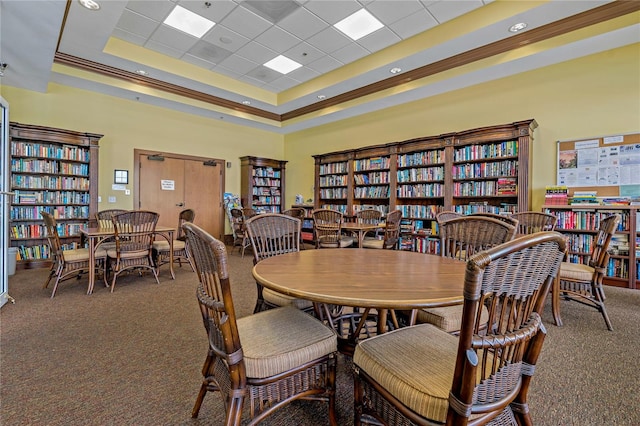 carpeted dining space featuring a raised ceiling, crown molding, a drop ceiling, and a towering ceiling