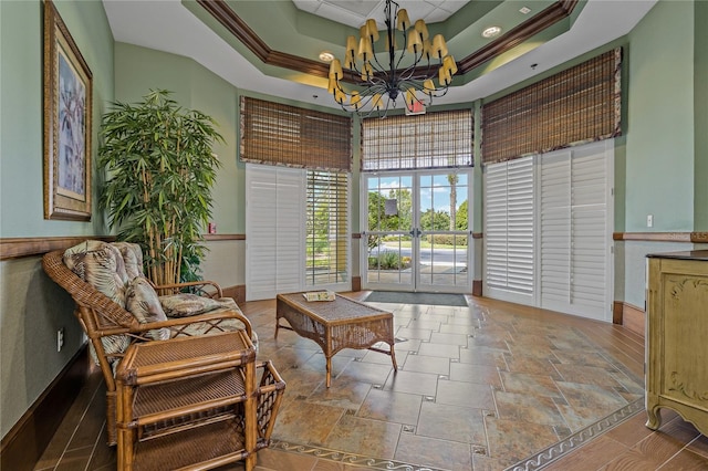 living area with a chandelier, french doors, a raised ceiling, and ornamental molding