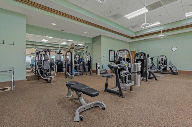 exercise room featuring a raised ceiling, a paneled ceiling, and carpet