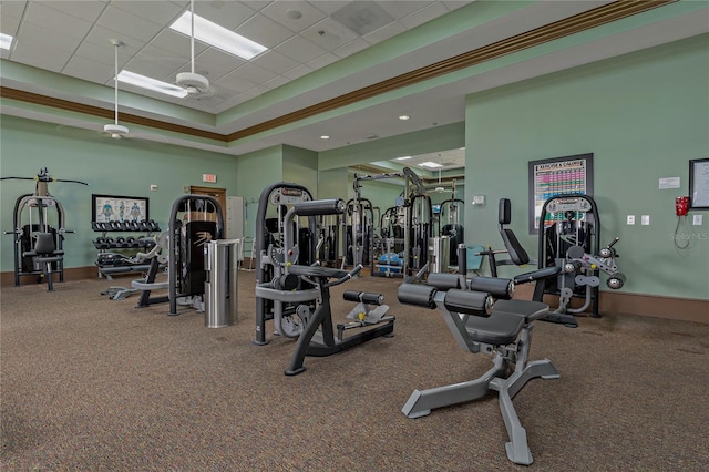 exercise room featuring carpet flooring, a paneled ceiling, a tray ceiling, and crown molding