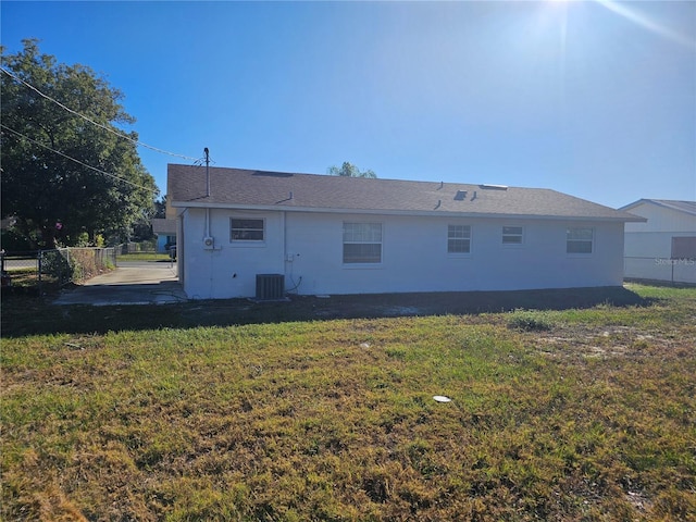 back of house with central AC unit and a lawn