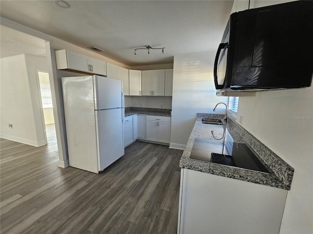 kitchen with a textured ceiling, sink, white refrigerator, dark hardwood / wood-style floors, and white cabinetry