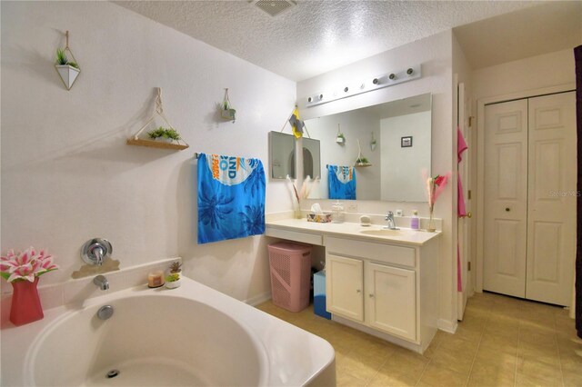 bathroom featuring vanity, a bath, a textured ceiling, and tile patterned flooring