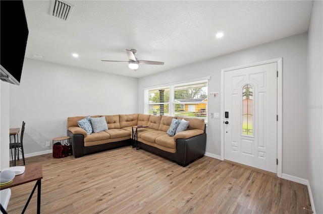 living room with a textured ceiling, light wood-type flooring, and ceiling fan