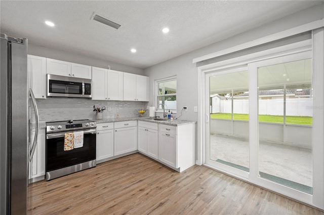 kitchen featuring sink, light hardwood / wood-style flooring, light stone countertops, white cabinetry, and stainless steel appliances