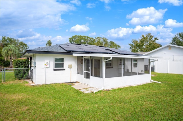 back of house with solar panels, a lawn, and a sunroom