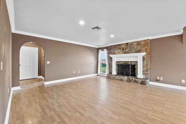 unfurnished living room featuring a fireplace, a textured ceiling, light hardwood / wood-style flooring, and crown molding