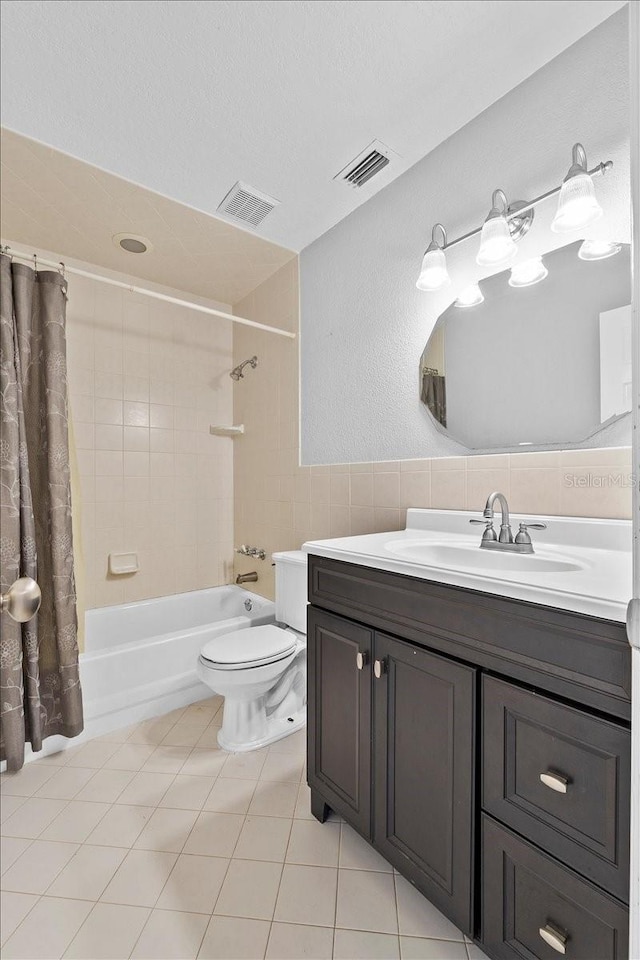 full bathroom with vanity, tile patterned flooring, toilet, tile walls, and shower / tub combo