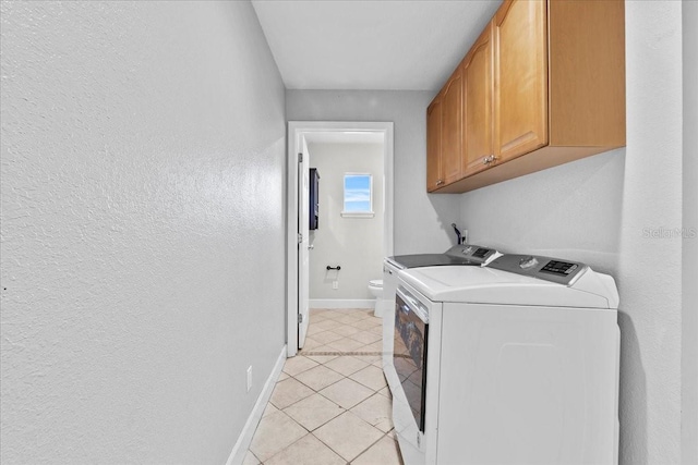 laundry room with washer and dryer, cabinets, and light tile patterned floors