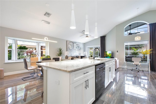 kitchen featuring white cabinetry, hanging light fixtures, dishwasher, an island with sink, and light stone countertops