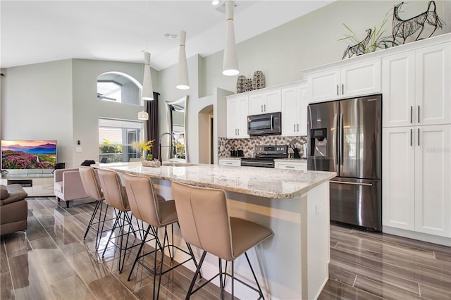 kitchen with stainless steel appliances, sink, a center island with sink, and white cabinets