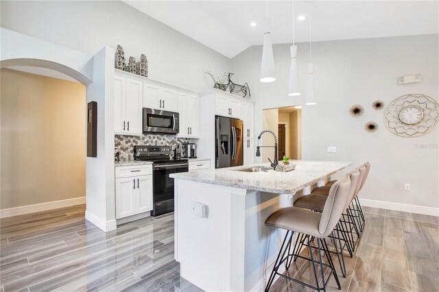 1591 Forest Hills Ln, Haines City, FL 33844 - kitchen featuring appliances with stainless steel finishes, a sink, a kitchen bar, a kitchen island with sink, and white cabinets