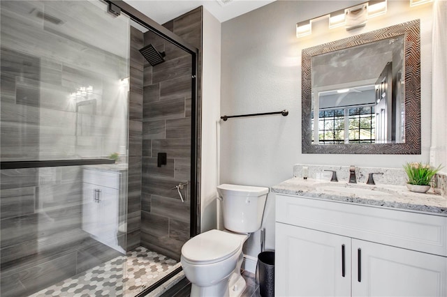 bathroom featuring a shower with door, vanity, and toilet