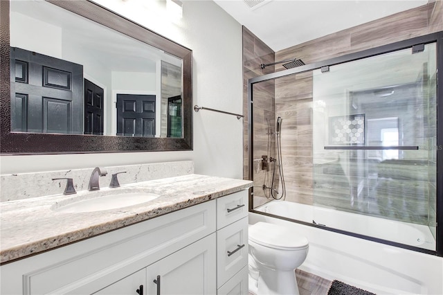 full bathroom with enclosed tub / shower combo, vanity, and toilet