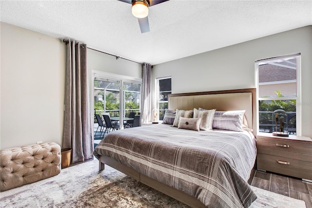 bedroom with ceiling fan, dark wood-type flooring, access to outside, and a textured ceiling