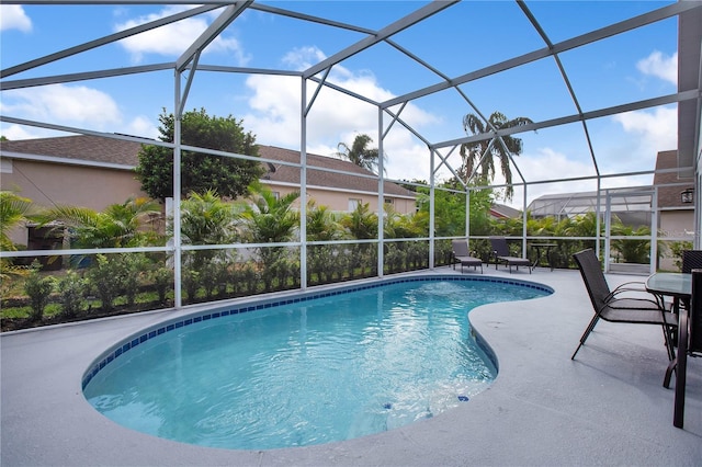 view of pool with glass enclosure and a patio area