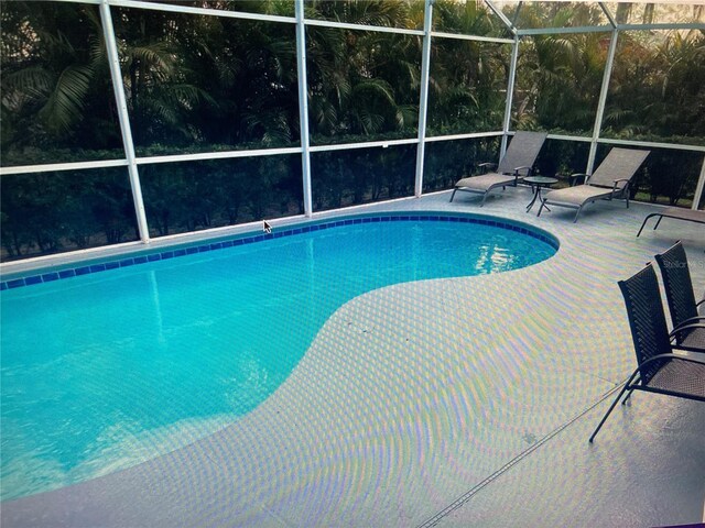 view of pool with a patio and glass enclosure