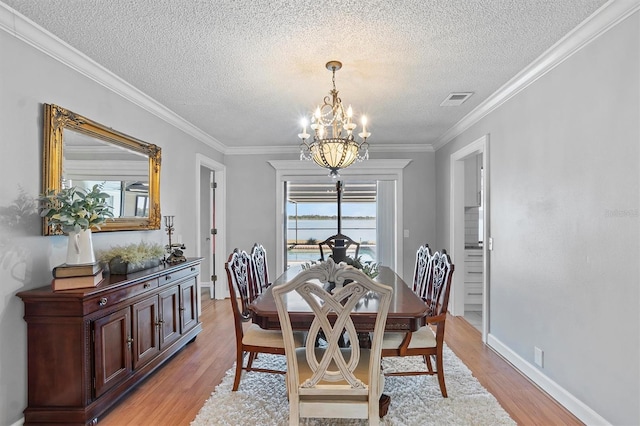 dining room featuring crown molding, visible vents, a notable chandelier, and light wood-style flooring