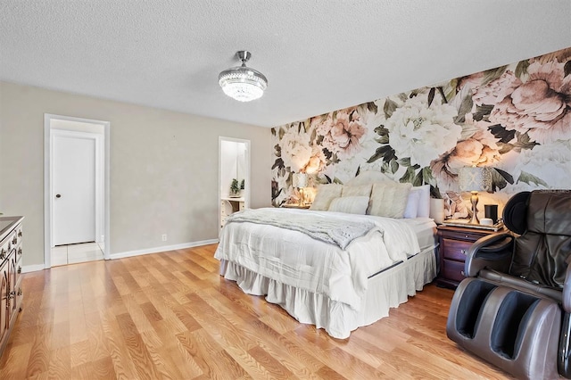 bedroom with baseboards, a textured ceiling, and light wood finished floors