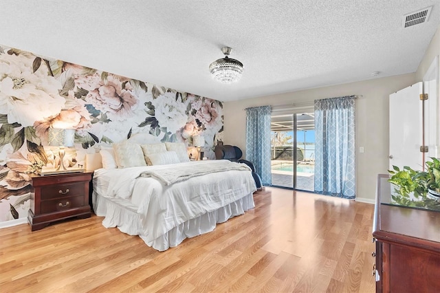 bedroom with visible vents, a textured ceiling, wood finished floors, access to outside, and baseboards