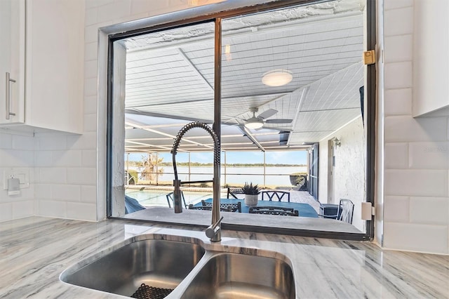 kitchen featuring white cabinets, a sunroom, a wealth of natural light, and a sink