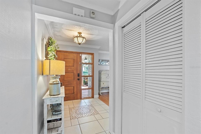 entryway with crown molding and light tile patterned floors