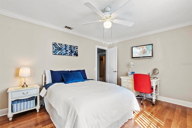 bedroom with crown molding, visible vents, a ceiling fan, wood finished floors, and baseboards