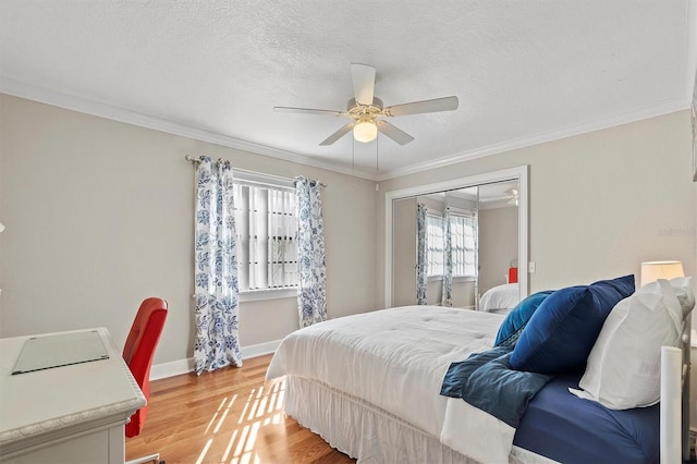 bedroom featuring baseboards, light wood-style flooring, ornamental molding, a textured ceiling, and a closet