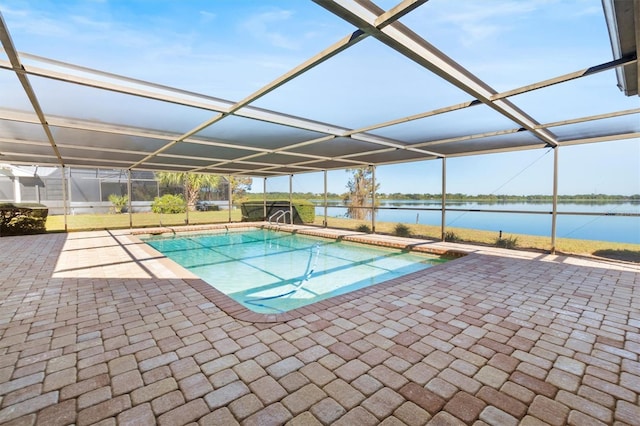 pool featuring glass enclosure, a patio area, and a water view