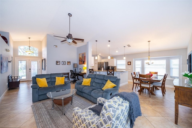 tiled living room featuring ceiling fan with notable chandelier, a healthy amount of sunlight, high vaulted ceiling, and french doors