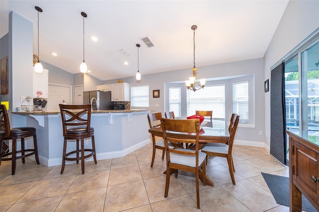 tiled dining room with plenty of natural light, a chandelier, and lofted ceiling