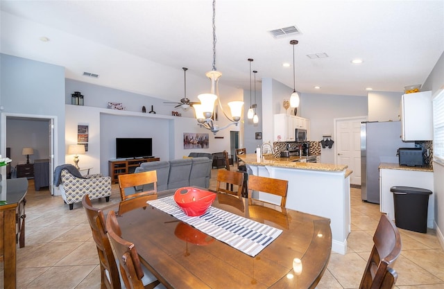 dining area with ceiling fan with notable chandelier, light tile patterned flooring, and lofted ceiling