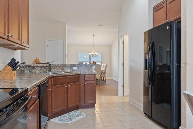 kitchen with sink, a notable chandelier, pendant lighting, light tile patterned flooring, and black appliances