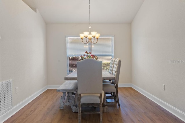 dining space with wood-type flooring and an inviting chandelier