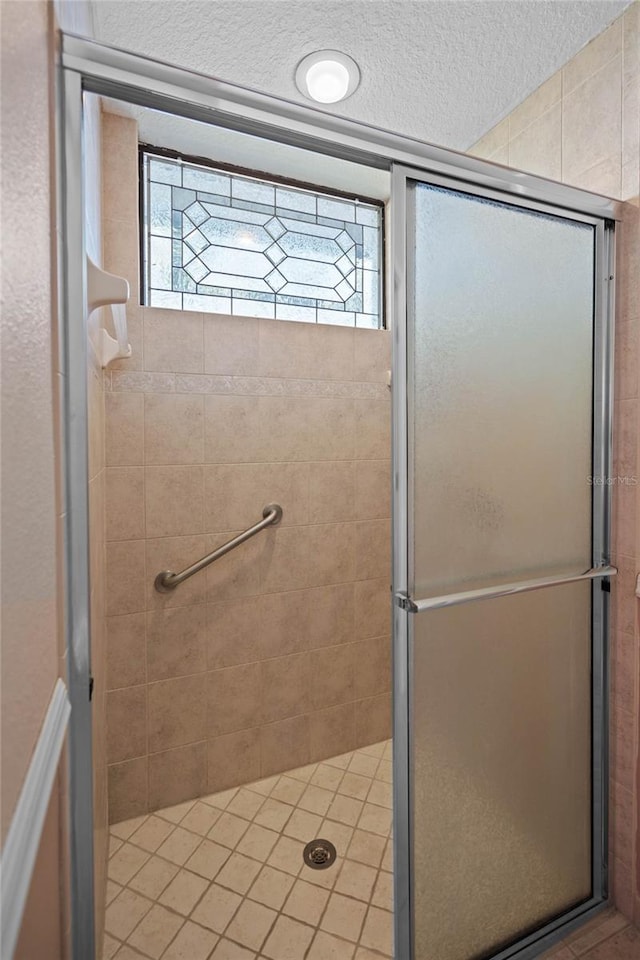 bathroom featuring a shower with shower door and a textured ceiling