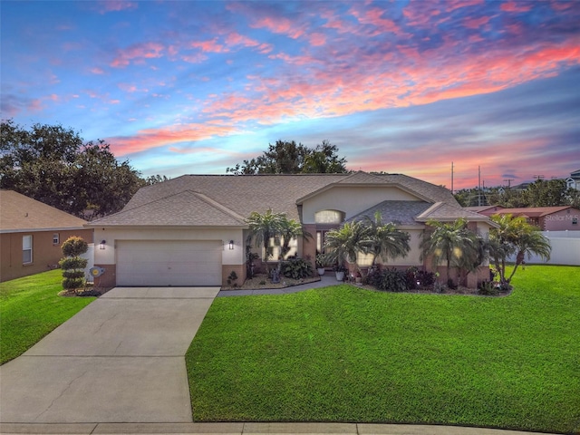 ranch-style home featuring a garage and a lawn