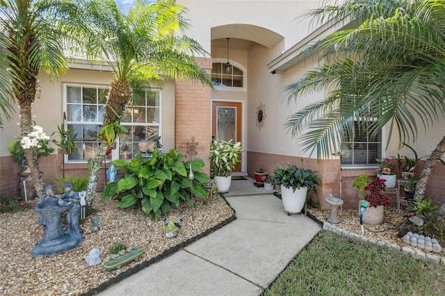 view of exterior entry featuring brick siding and stucco siding