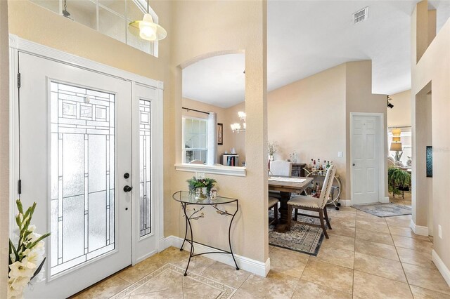 foyer featuring a high ceiling, light tile patterned floors, and an inviting chandelier