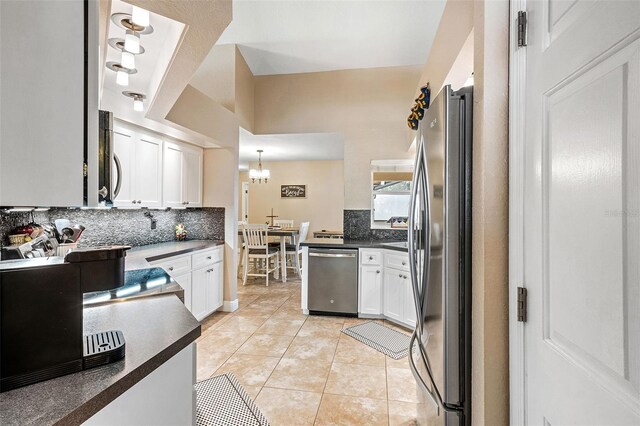 kitchen featuring light tile patterned flooring, tasteful backsplash, hanging light fixtures, stainless steel appliances, and white cabinets