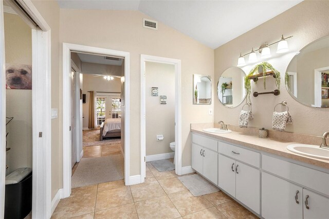 bathroom featuring lofted ceiling, vanity, tile patterned flooring, and toilet