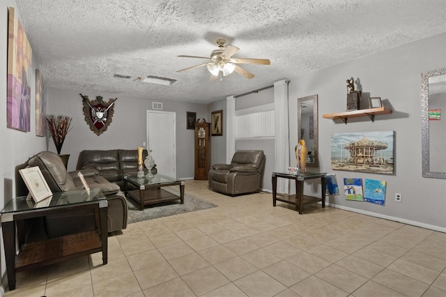 living room featuring ceiling fan, light tile patterned floors, and a textured ceiling