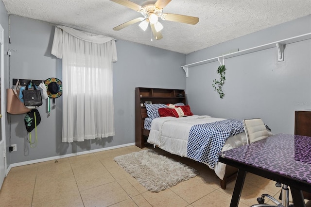 bedroom with ceiling fan, light tile patterned floors, and a textured ceiling