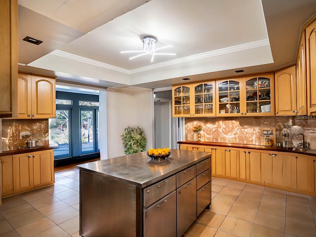 kitchen with a center island, sink, a raised ceiling, decorative backsplash, and light tile patterned flooring