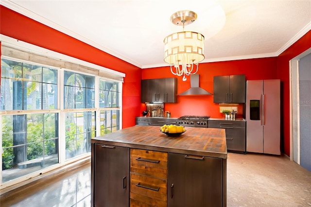 kitchen with wood counters, appliances with stainless steel finishes, wall chimney exhaust hood, pendant lighting, and a kitchen island